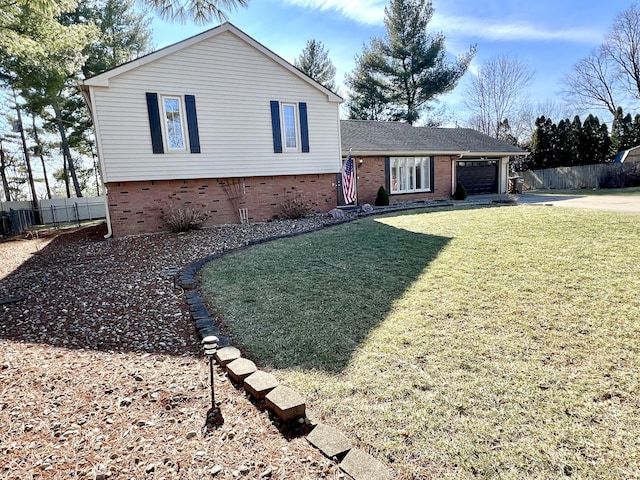 tri-level home with brick siding, fence, a garage, driveway, and a front lawn