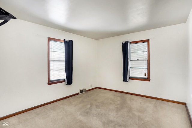 carpeted spare room with visible vents and baseboards