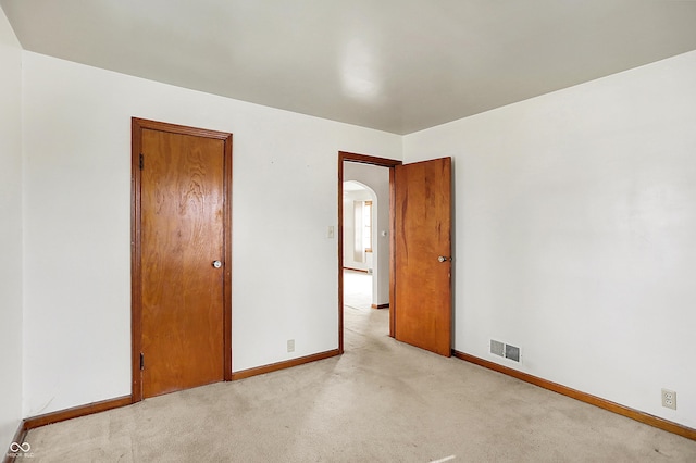 unfurnished bedroom with carpet floors, baseboards, visible vents, and arched walkways