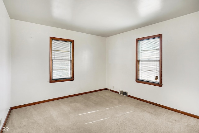 empty room featuring carpet flooring, visible vents, and baseboards