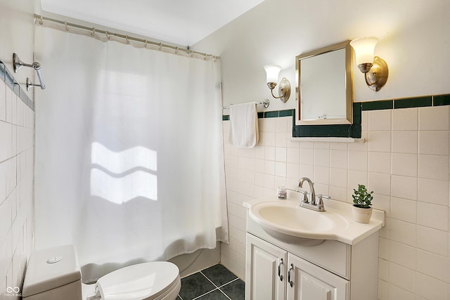 bathroom with tile patterned flooring, toilet, shower / tub combo, vanity, and tile walls