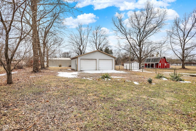 view of yard featuring a barn, an outdoor structure, a detached garage, and fence