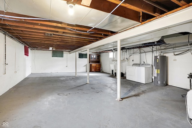 unfinished basement with electric water heater, a sink, and washer and clothes dryer