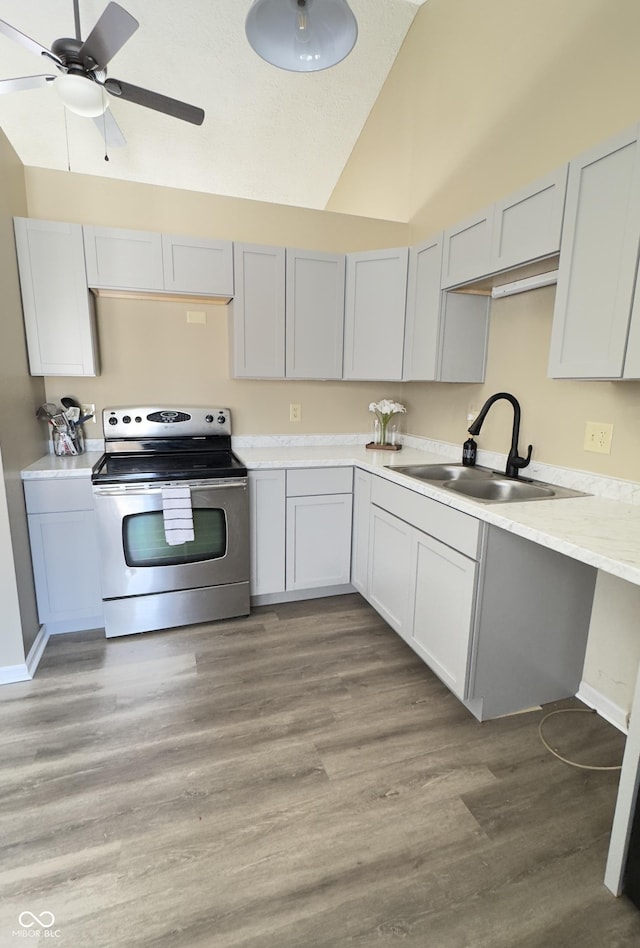 kitchen featuring ceiling fan, electric range, a sink, light wood-style floors, and light countertops