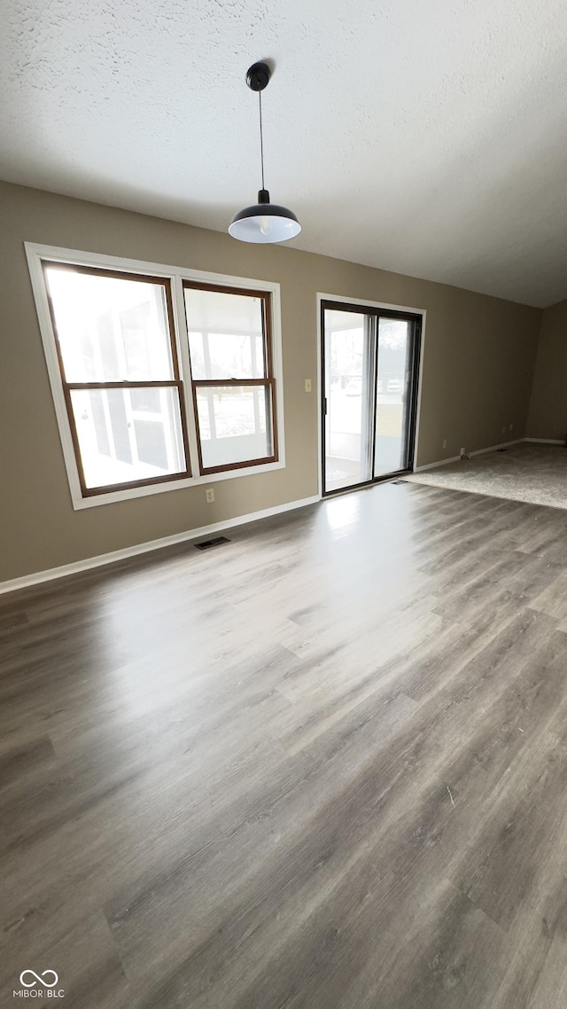 unfurnished living room with visible vents, dark wood finished floors, a textured ceiling, and baseboards