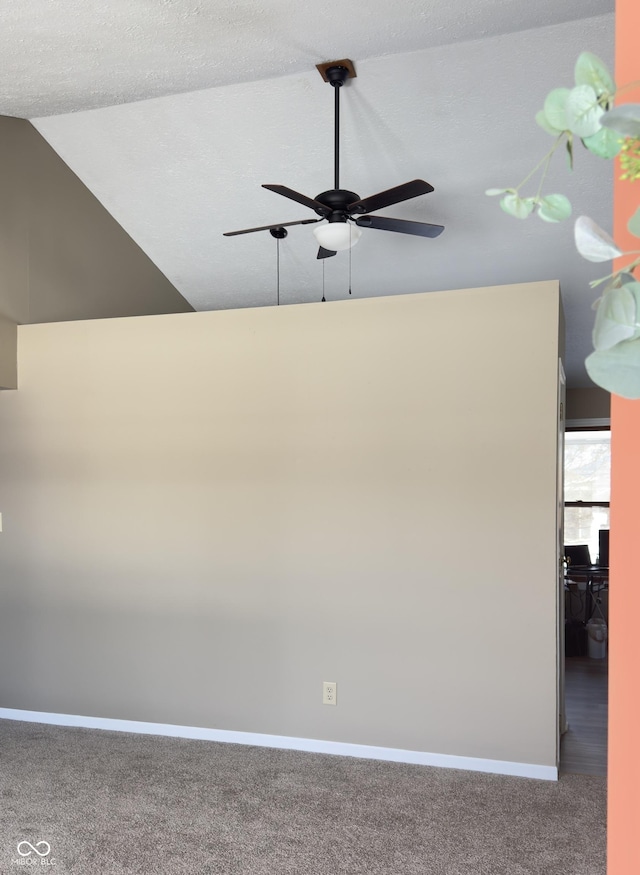 carpeted empty room featuring lofted ceiling, ceiling fan, and baseboards