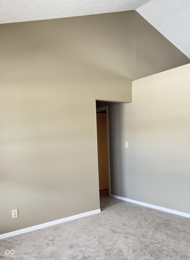 unfurnished room featuring carpet flooring, vaulted ceiling, and baseboards