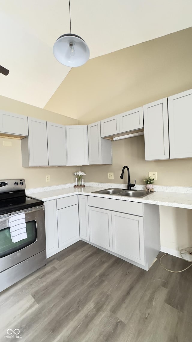 kitchen featuring stainless steel electric range oven, light countertops, white cabinetry, pendant lighting, and a sink