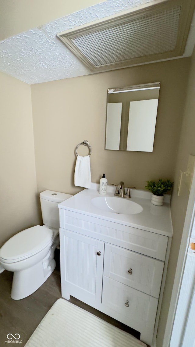 bathroom with toilet, wood finished floors, and vanity