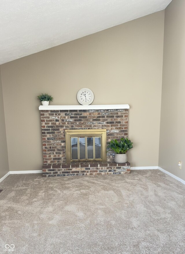 unfurnished living room featuring carpet, a fireplace, vaulted ceiling, a textured ceiling, and baseboards