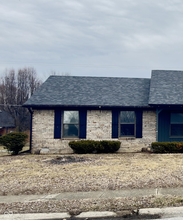 single story home featuring a shingled roof and brick siding