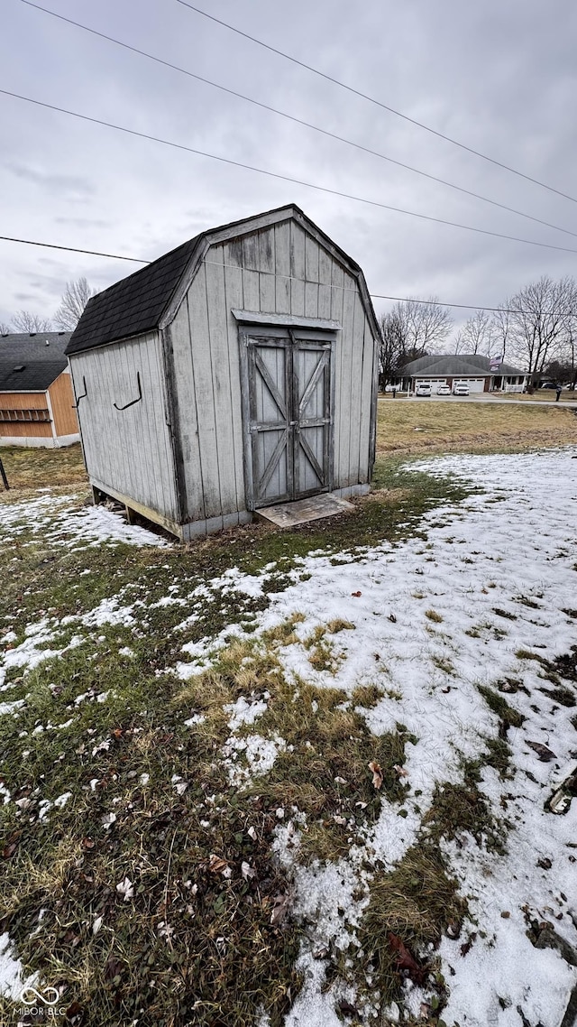 snow covered structure featuring a shed and an outdoor structure