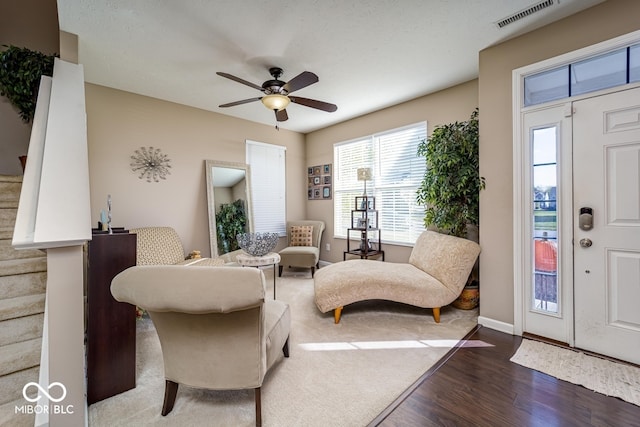 living room featuring a ceiling fan, baseboards, visible vents, and dark wood-type flooring