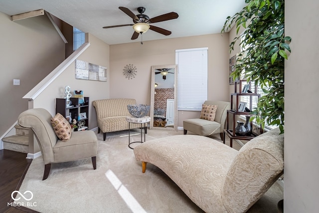 living area with baseboards and a ceiling fan