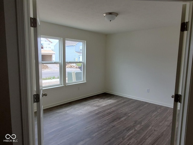 empty room with baseboards and dark wood-style flooring