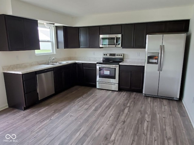 kitchen featuring light wood finished floors, appliances with stainless steel finishes, light countertops, and a sink