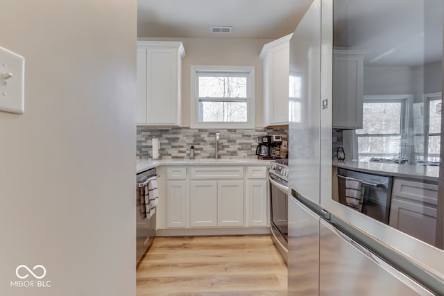 kitchen featuring a sink, visible vents, white cabinetry, appliances with stainless steel finishes, and tasteful backsplash