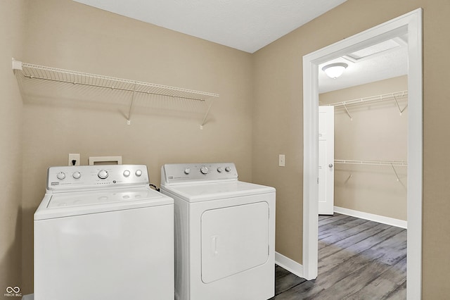 washroom featuring washer and dryer, laundry area, baseboards, and wood finished floors