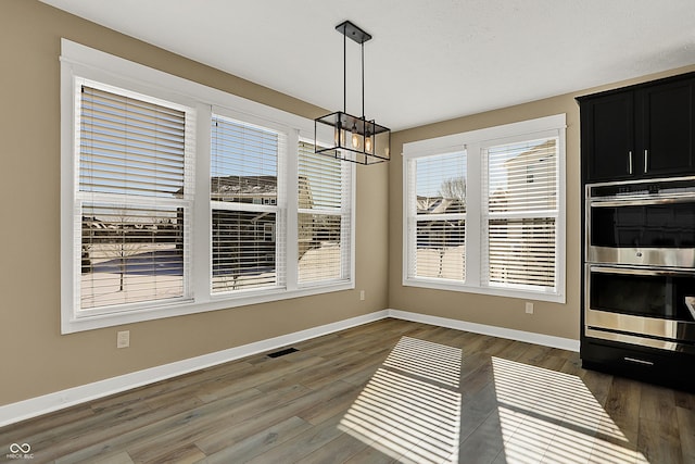 dining area featuring dark wood-type flooring, visible vents, baseboards, and an inviting chandelier