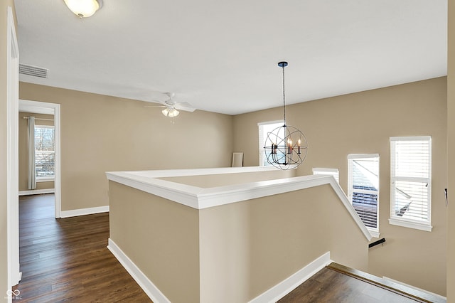 hall featuring visible vents, dark wood-type flooring, an upstairs landing, a chandelier, and baseboards