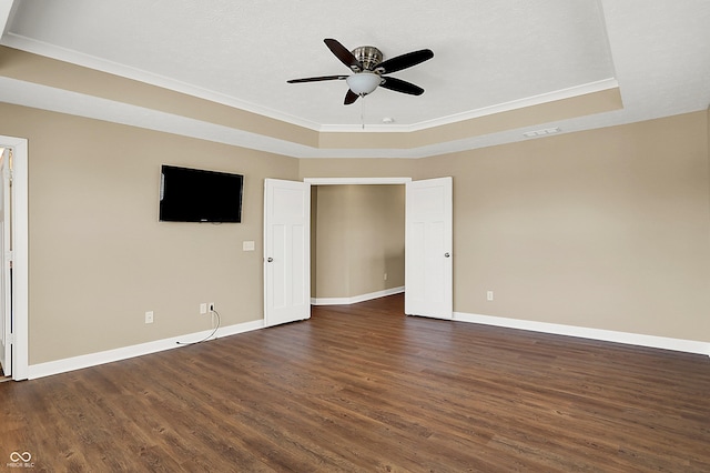 spare room featuring baseboards, a tray ceiling, ceiling fan, and dark wood-type flooring