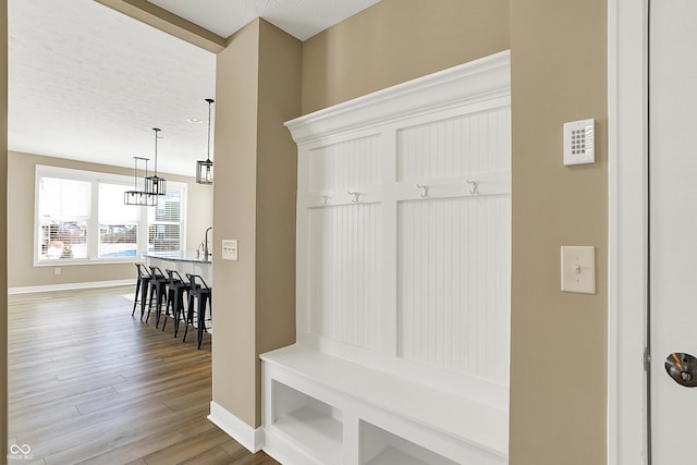 mudroom featuring a textured ceiling, wood finished floors, and baseboards