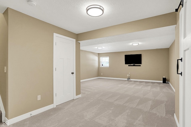 basement featuring light carpet, baseboards, and a textured ceiling