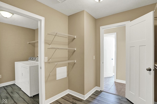 laundry area featuring a textured ceiling, washing machine and dryer, laundry area, wood finished floors, and baseboards