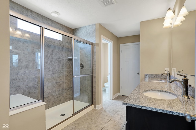 full bath with toilet, a shower stall, visible vents, and a sink