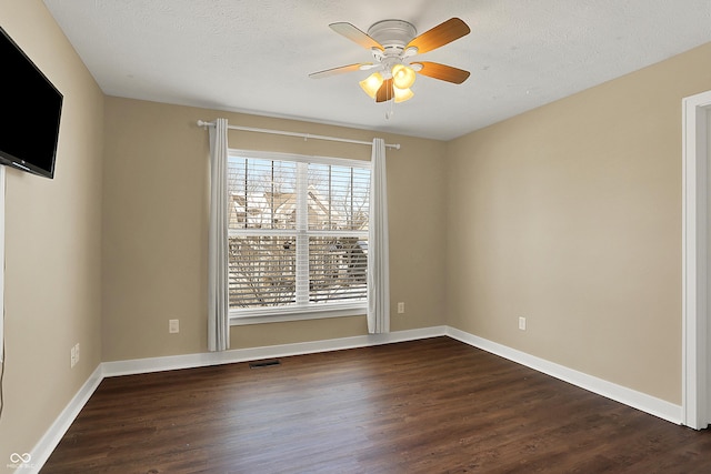 empty room featuring a ceiling fan, a textured ceiling, baseboards, and dark wood-style flooring