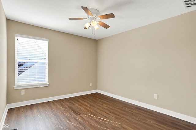 spare room with dark wood-style floors, baseboards, visible vents, and ceiling fan