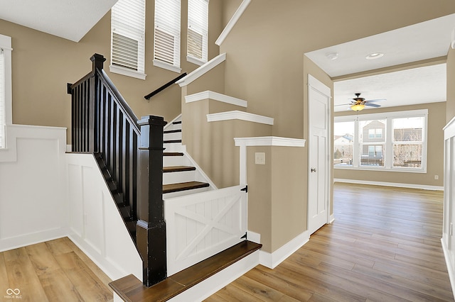 stairs with recessed lighting, wood finished floors, a ceiling fan, and baseboards