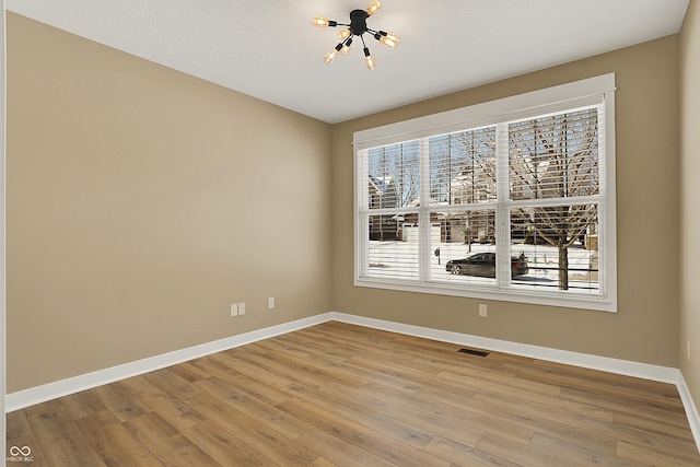 unfurnished room featuring visible vents, baseboards, and wood finished floors