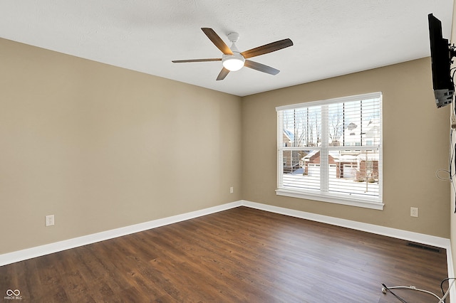 spare room with dark wood-style flooring, visible vents, ceiling fan, a textured ceiling, and baseboards