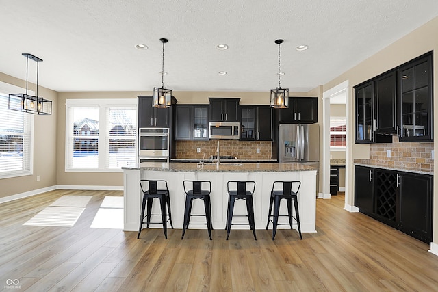 kitchen with appliances with stainless steel finishes, glass insert cabinets, and dark cabinets