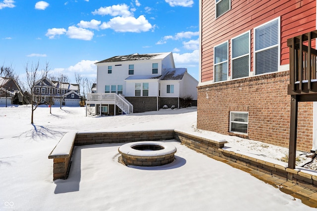 snow covered patio featuring an outdoor fire pit, a residential view, and stairway