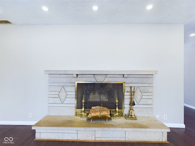 interior details with a textured ceiling, wood finished floors, visible vents, and baseboards