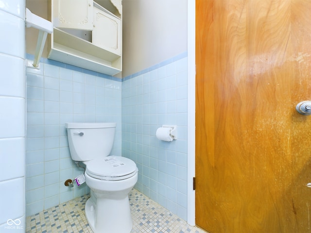 half bath featuring tile walls, toilet, and tile patterned floors