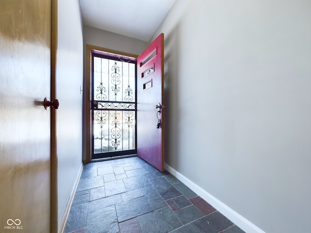 doorway to outside with stone tile flooring and baseboards