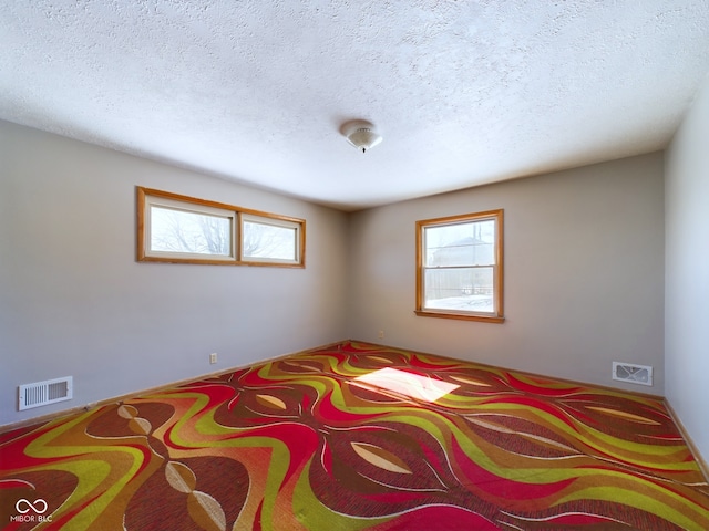 carpeted bedroom with multiple windows, visible vents, and a textured ceiling