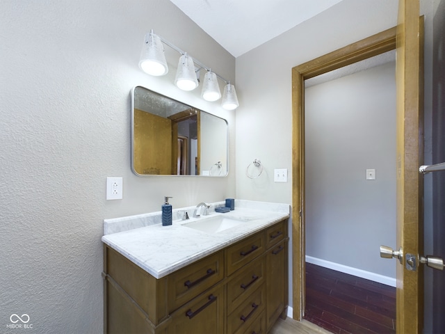 bathroom featuring vanity, baseboards, and wood finished floors