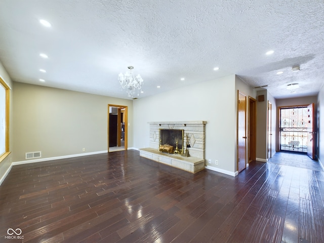 unfurnished living room featuring dark wood-style flooring, visible vents, a stone fireplace, and baseboards