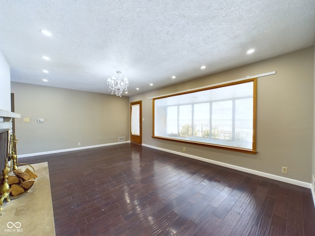 unfurnished living room featuring dark wood-type flooring, visible vents, a fireplace, and an inviting chandelier