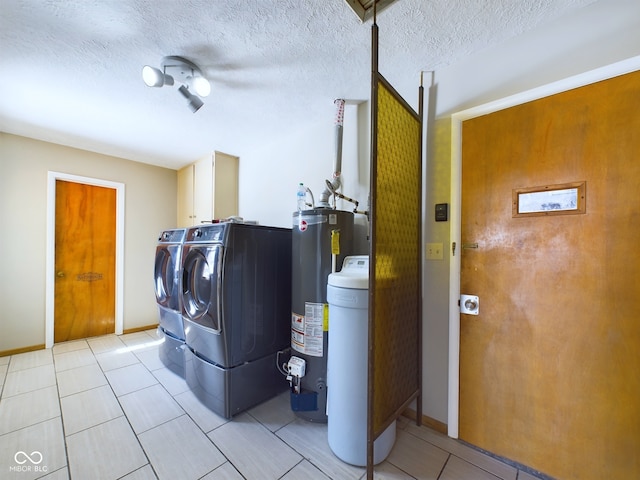 washroom with gas water heater, light tile patterned floors, cabinet space, a textured ceiling, and separate washer and dryer