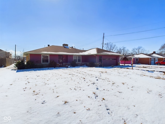 snow covered rear of property featuring a garage