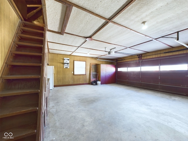 garage with wood walls, freestanding refrigerator, and a garage door opener