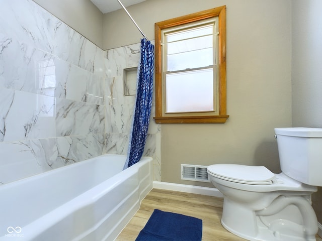 full bathroom with toilet, wood finished floors, visible vents, baseboards, and shower / bath combo