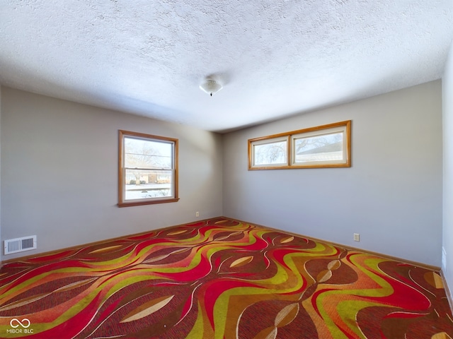 bedroom featuring visible vents, a textured ceiling, and multiple windows