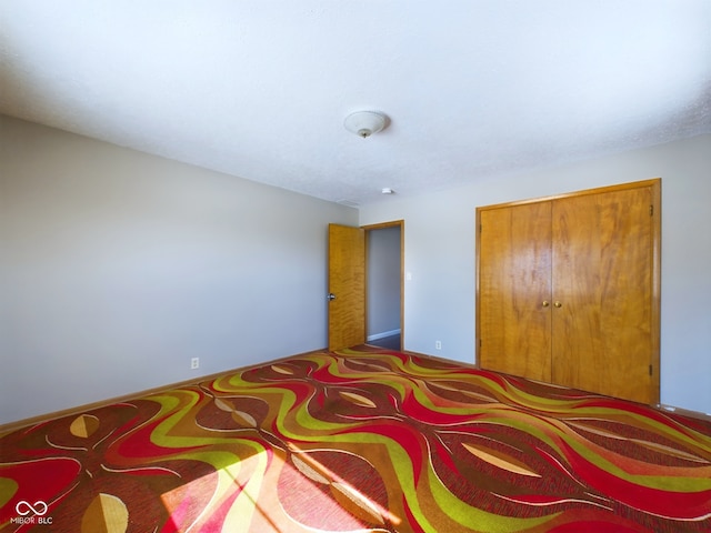 carpeted bedroom with a closet and baseboards