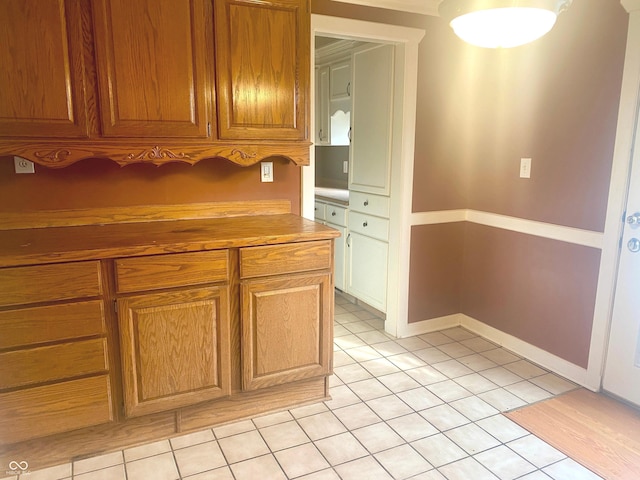 kitchen featuring light tile patterned floors, baseboards, and brown cabinetry